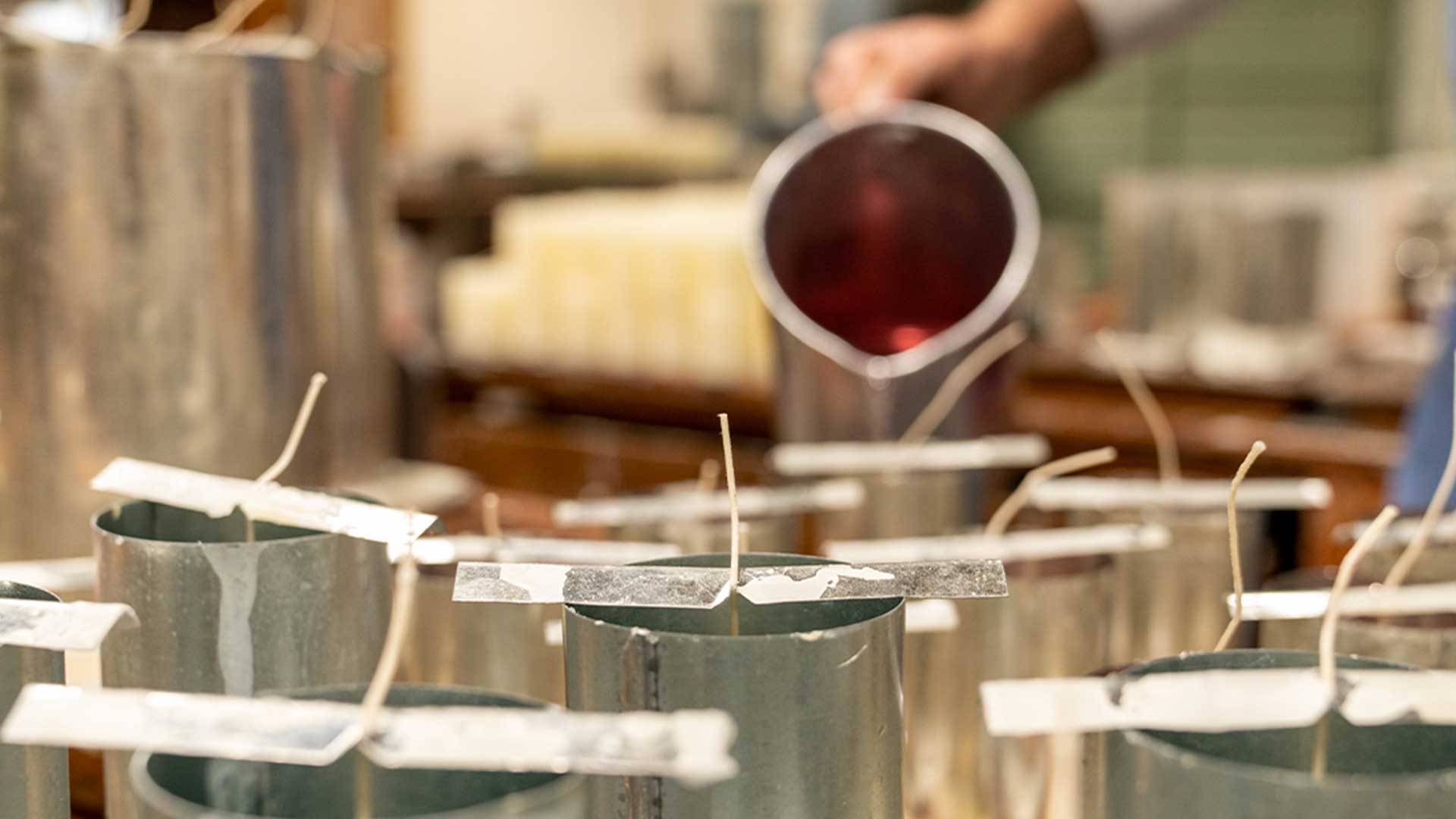 Worker pouring candle wax into pillar molds.
