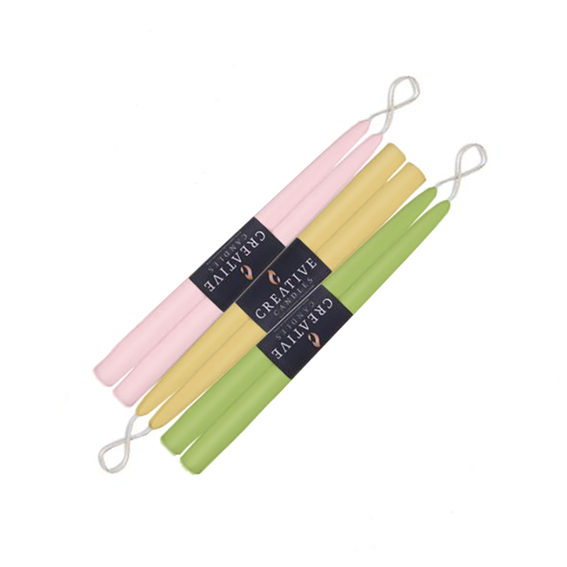 Set of three pastel-colored candles with a visible brand label on a white background
