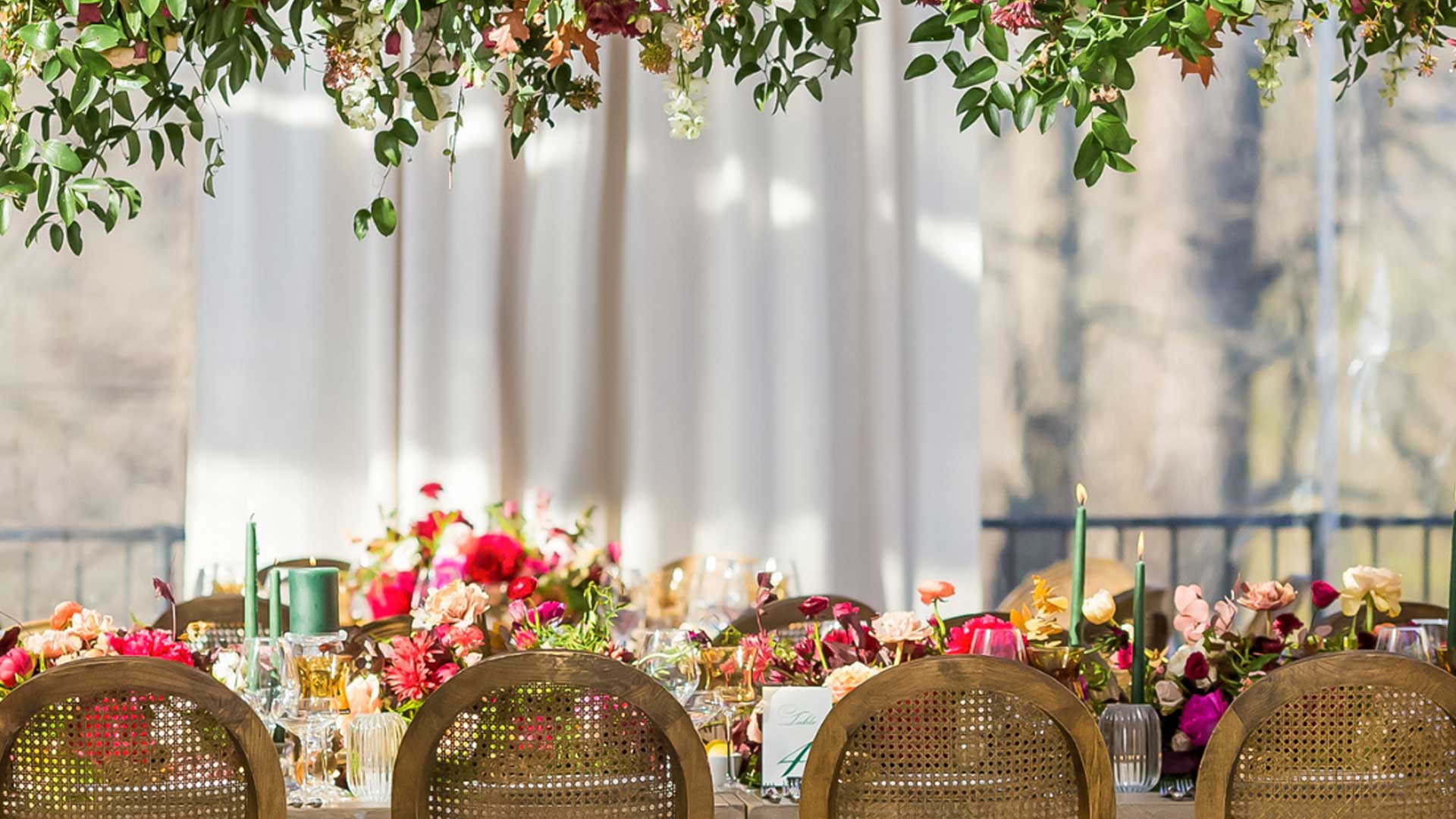 Eucalyptus colored taper candles and pillar candles lit on a decorated event table.