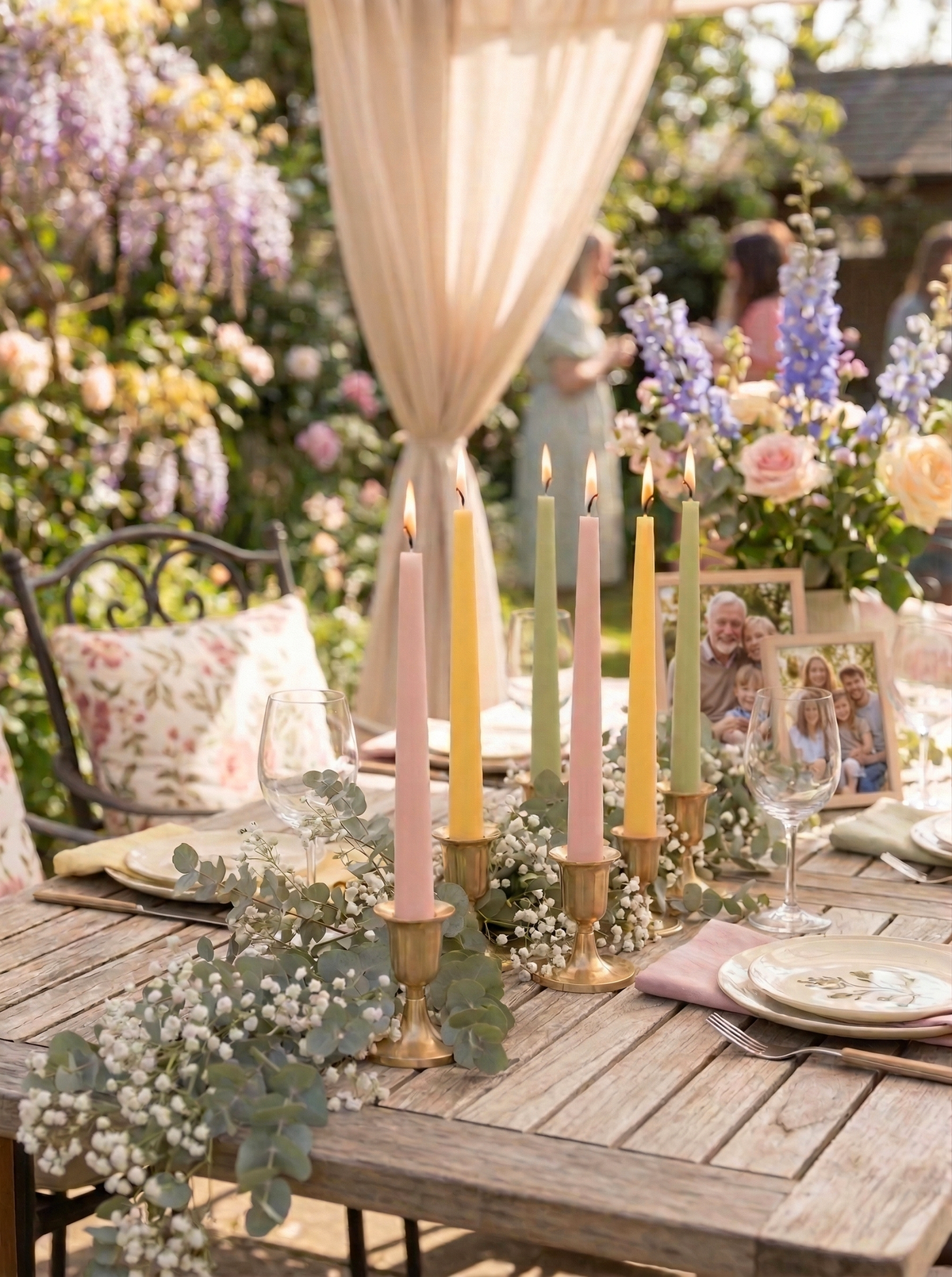 Outdoor garden party with a decorated table featuring candles and flowers.