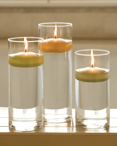 3 clear glasses with floating candles lit