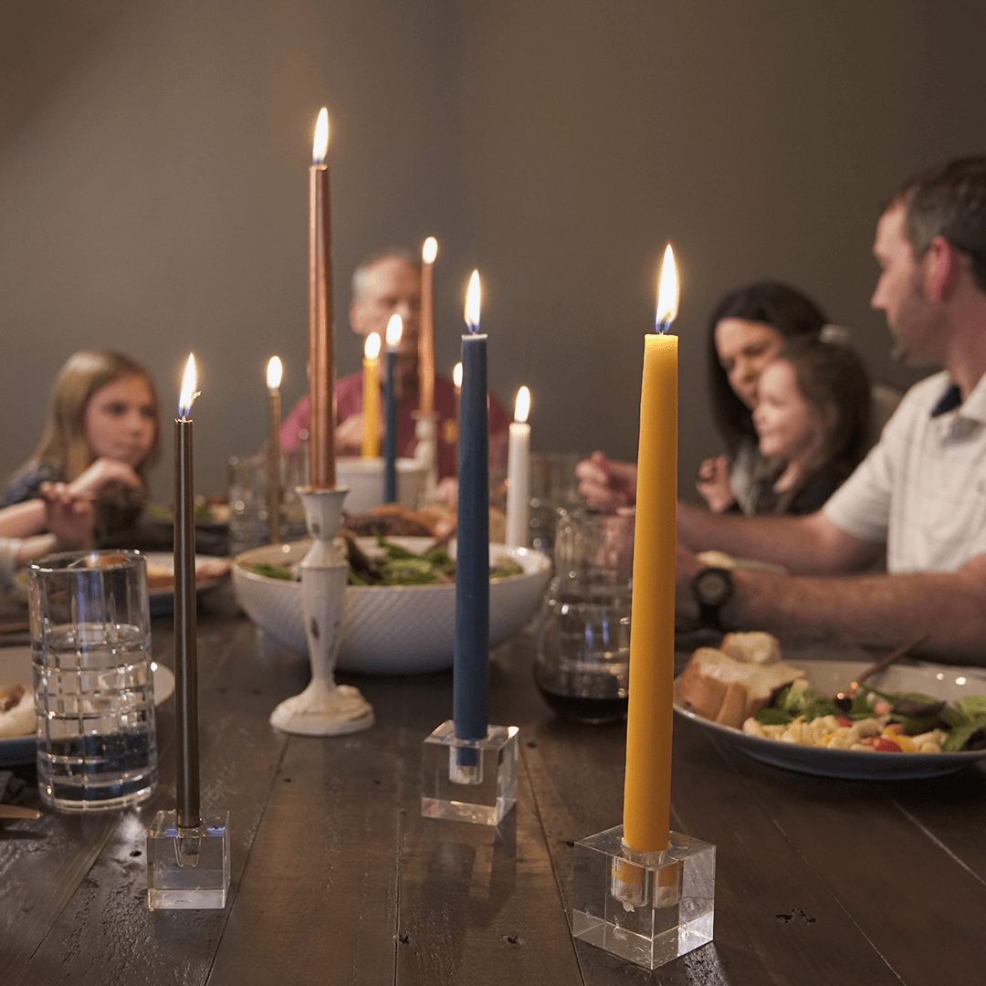 Pink taper candle burning beside a bottle of rose wine on a blue floral tablecloth